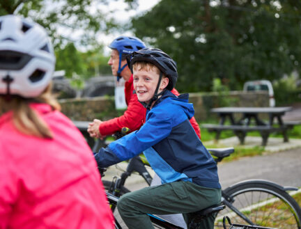 Family cycling near Killarney's Park Place Apartments on a bright day.