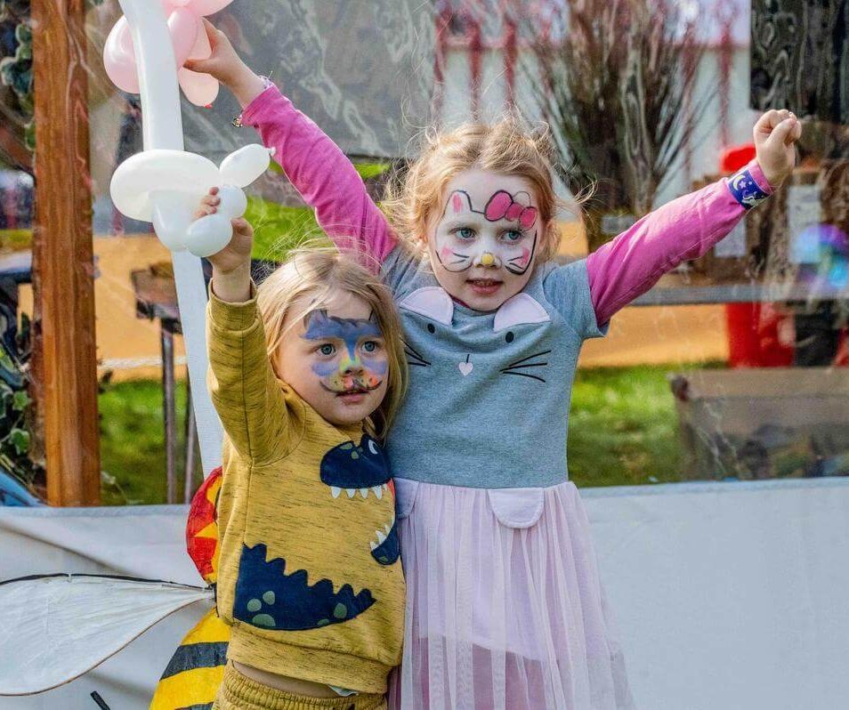 Two children with face paint playing at Park Place Apartments, Killarney, with balloons in hand.