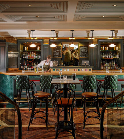 A cosy bar at Park Place Apartments in Killarney with seating and a bartender serving drinks.