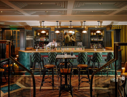 A cosy bar at Park Place Apartments in Killarney with seating and a bartender serving drinks.