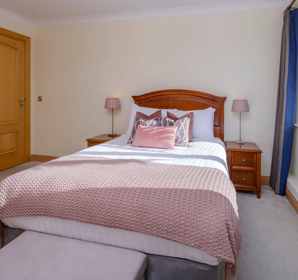 Cosy bedroom with pink accents in Park Place Apartments, Killarney, showcasing natural light.