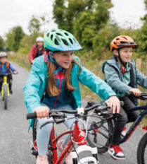 Family cycling on a scenic path near Killarney, enjoying a sunny day outdoors.