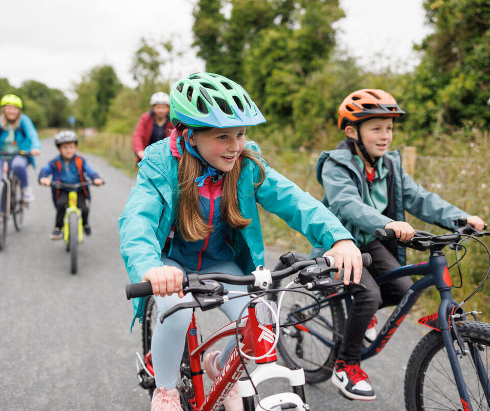 Family cycling on a scenic path near Killarney, enjoying a sunny day outdoors.