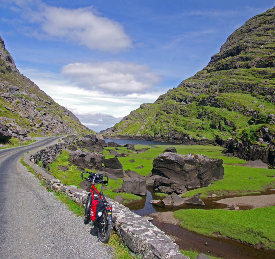 Scenic view of a bike on a tranquil road with lush green hills and blue sky near Killarney.