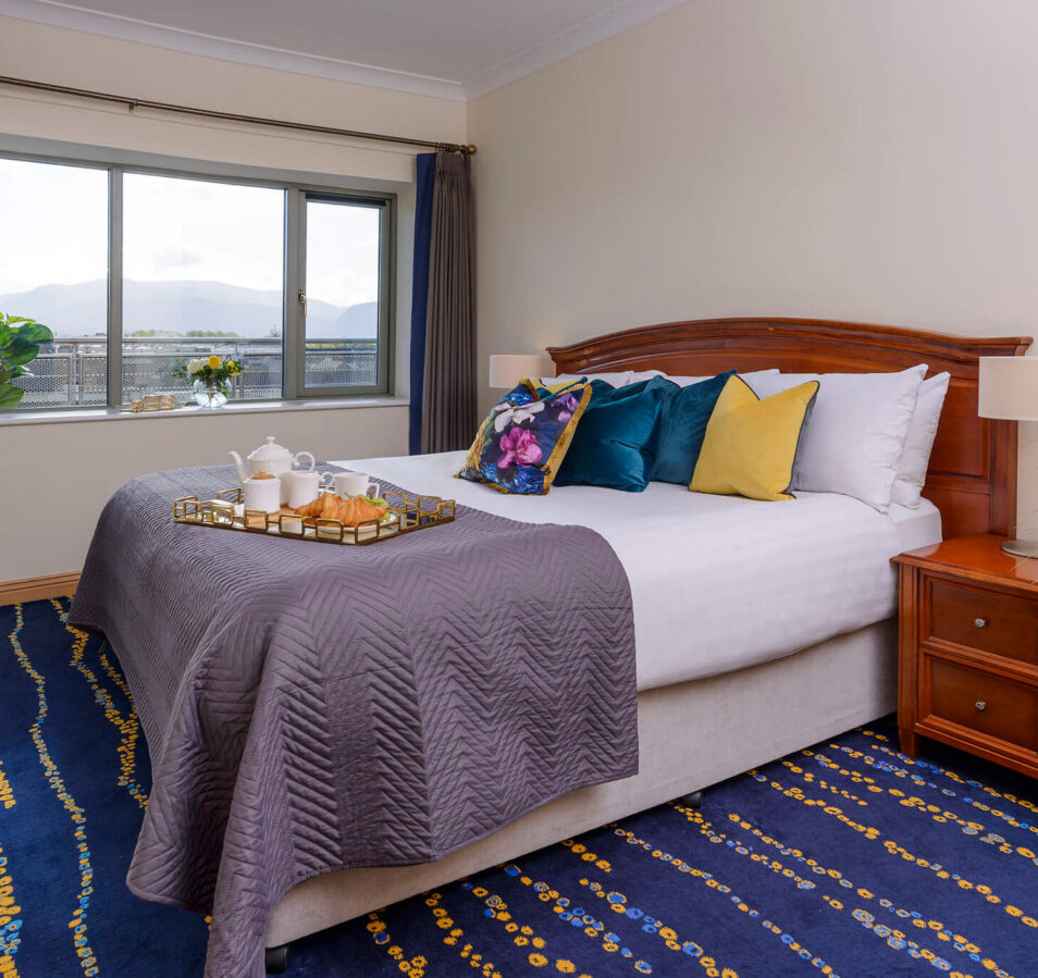 Cosy apartment bedroom with a scenic view, stylish decor, and breakfast tray on the bed.