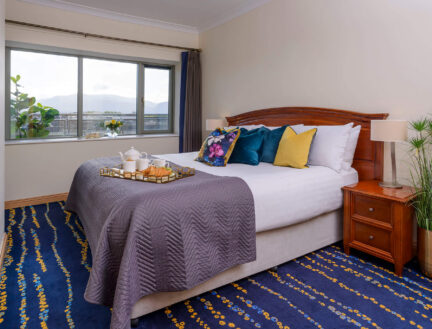 Cosy bedroom in Park Place Apartments, Killarney with plush bedding and scenic window view.