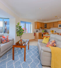 Cosy living area in Park Place Apartments with plush sofas, vibrant pillows, and a scenic view.