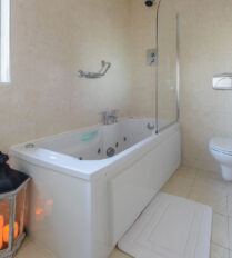 Elegant bathroom with bathtub, candles, and natural light at Park Place Apartments, Killarney.
