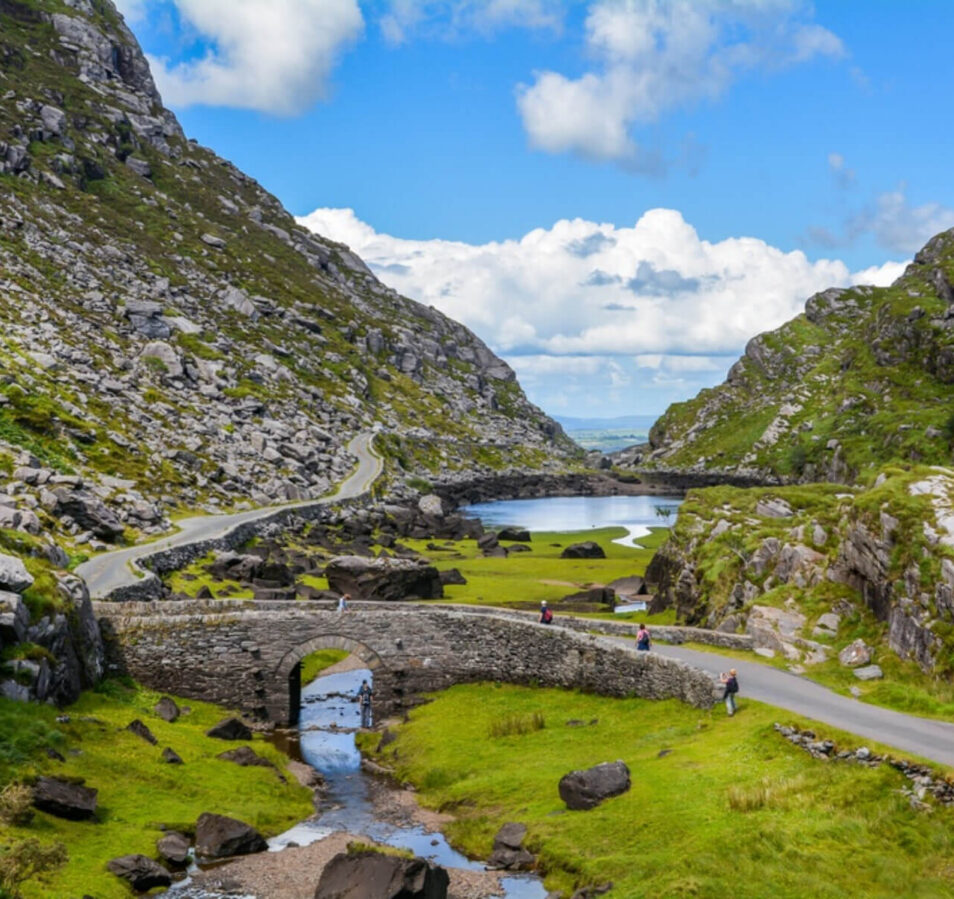 Scenic view of a stone bridge and winding road in green hills near Killarney, Ireland.