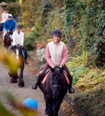 A family enjoys horse riding through lush greenery near Killarney, highlighting Park Place Apartments' nearby attractions.