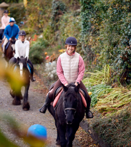 A family enjoys horse riding through lush greenery near Killarney, highlighting Park Place Apartments' nearby attractions.