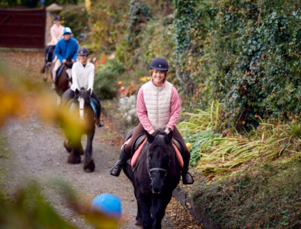 A family enjoys horse riding through lush greenery near Killarney, highlighting Park Place Apartments' nearby attractions.