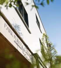 Modern Park Place Apartments facade with lush greenery and sunny blue sky in Killarney Town.