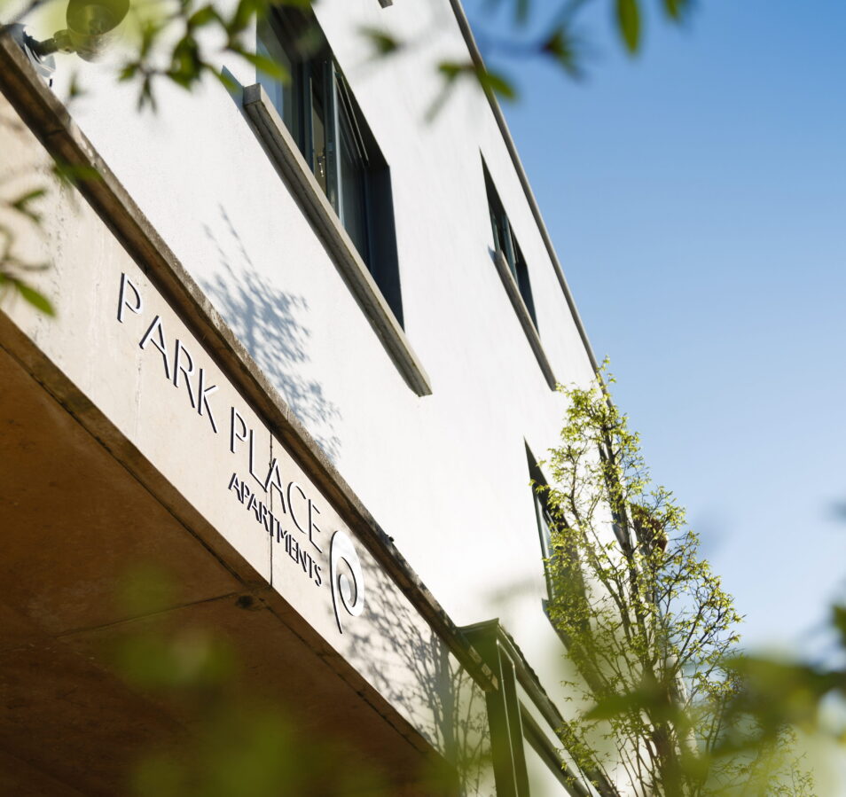 Modern Park Place Apartments facade with lush greenery and sunny blue sky in Killarney Town.