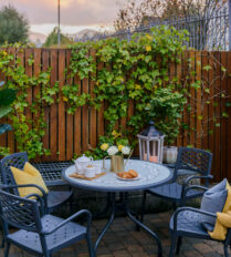 Cosy patio with a garden table, teapot, and croissants at sunset, Park Place Apartments.
