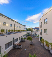 Spacious courtyard of Park Place Apartments in Killarney, with greenery and blue sky.
