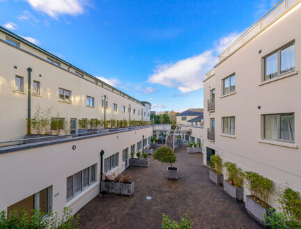 Spacious courtyard of Park Place Apartments in Killarney, with greenery and blue sky.