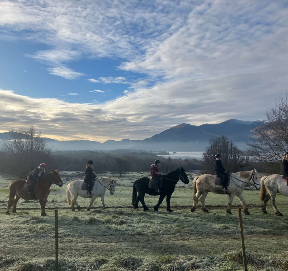 A group enjoys a morning horseback ride in a scenic, frosty Killarney landscape, mountains in view.