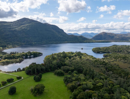 Scenic view of lush green landscape and serene lake near Killarney, ideal for family outings.