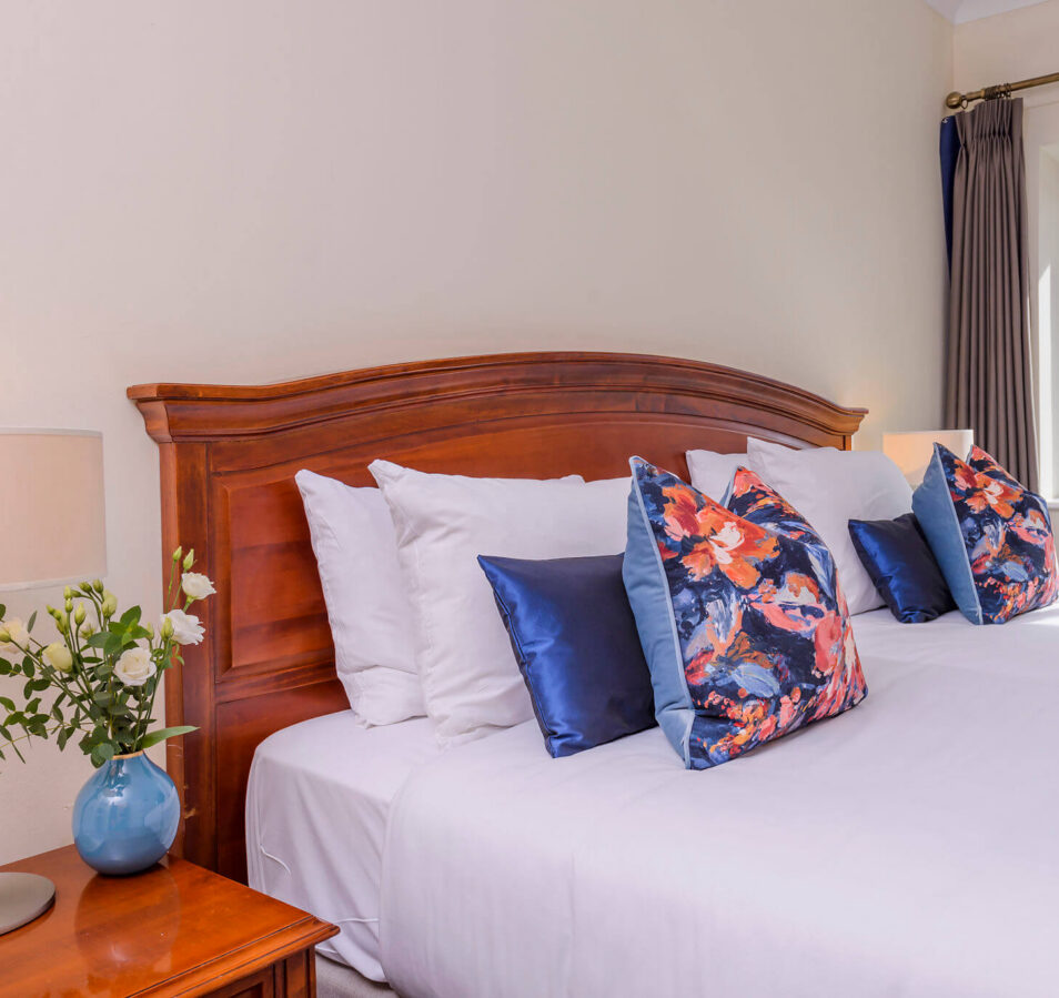 Comfortable bed with floral cushions in Park Place Apartments, Killarney.