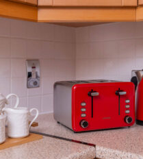 Cosy apartment kitchen with red kettle, toaster, and tea set on a countertop.