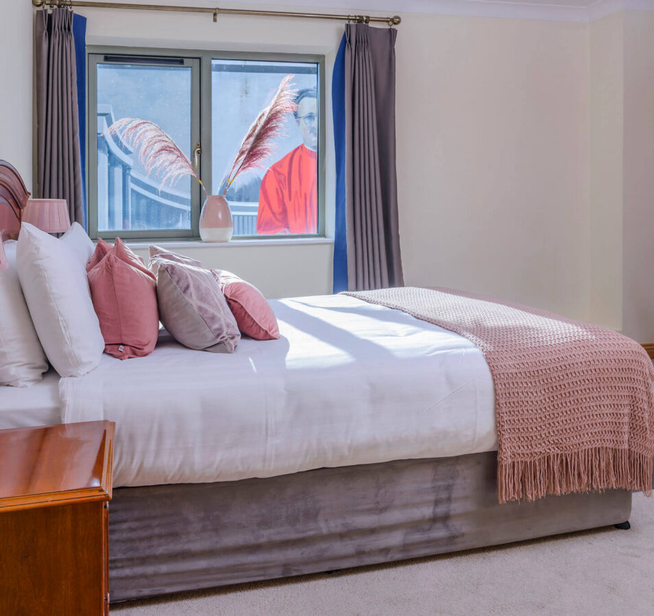 Cosy bedroom with pink decor in Park Place Apartments, Killarney, featuring a soft bed.