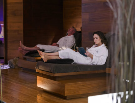A couple relaxes in robes at Park Place Apartments spa in Killarney, enjoying a peaceful atmosphere.