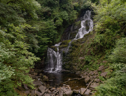 Scenic view of a tranquil waterfall surrounded by lush greenery in Killarney.