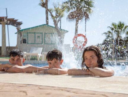 Children enjoying a sunny day by the pool at Park Place Apartments, with palm trees in the background.