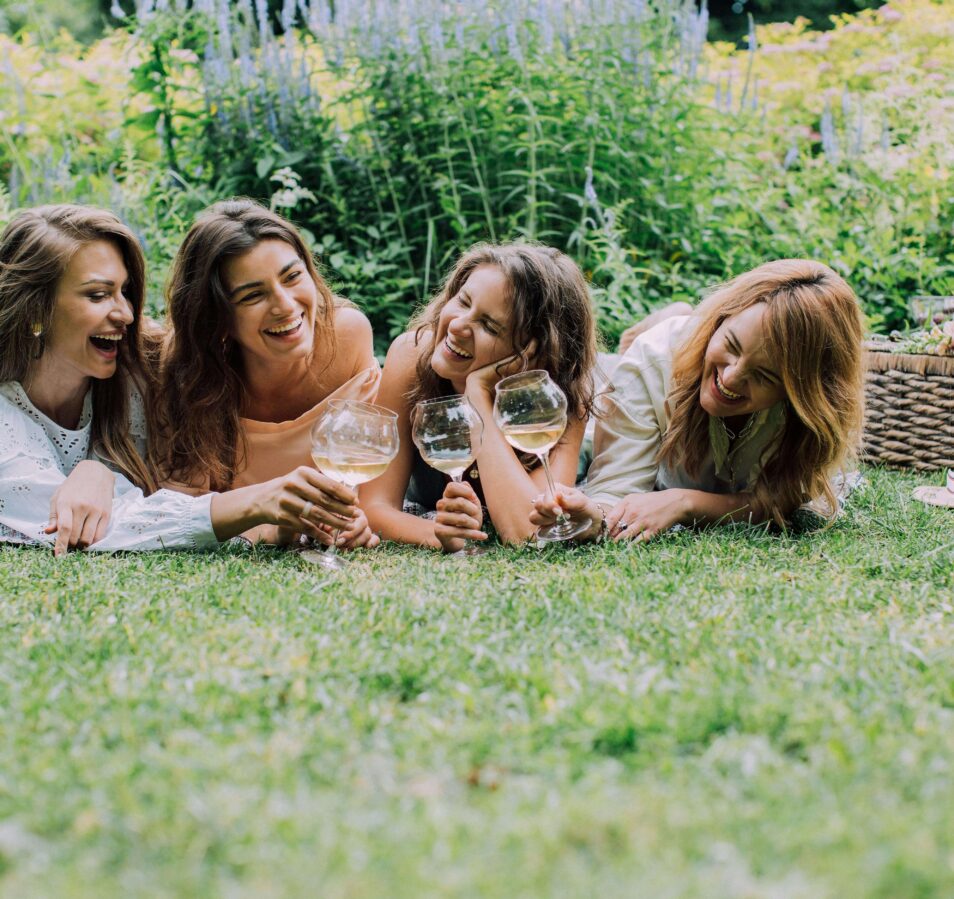 A group of friends enjoying a picnic on grass, with wine and flowers, at Park Place Apartments.