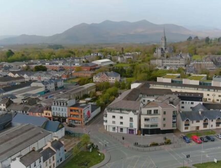 Aerial view of Killarney Town with apartments and scenic mountains in the background.