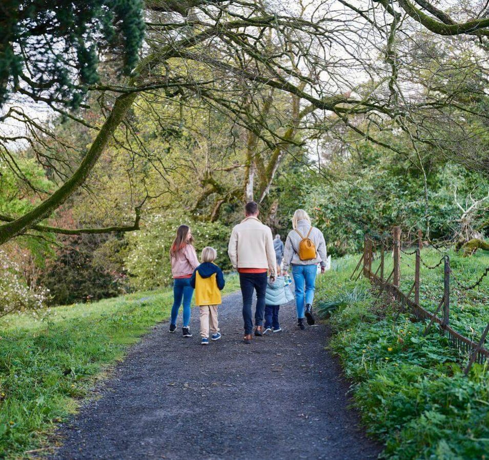 A family strolls through a lush, green park near Park Place Apartments in Killarney.