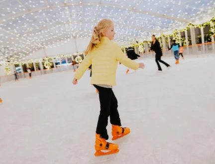 Family ice skating under festive lights at Park Place Apartments, Killarney.